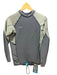 An O'Neill long-sleeve technical top laid flat on a wooden surface, featuring a dark gray center panel and light olive green ribbed sleeves and side panels, with a yellow hanger and retail tags visible.